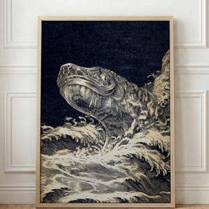 May include: A framed black and white illustration of a sea serpent emerging from turbulent waves. The artwork features detailed linework, with the serpent's head and open mouth prominently displayed against a dark background. The frame is a light wood color.