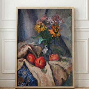 May include: A framed still life painting featuring a vase of colorful flowers, including yellow and orange blooms, and several red apples. The painting has a neutral color palette with a beige tablecloth and a blue patterned fabric.