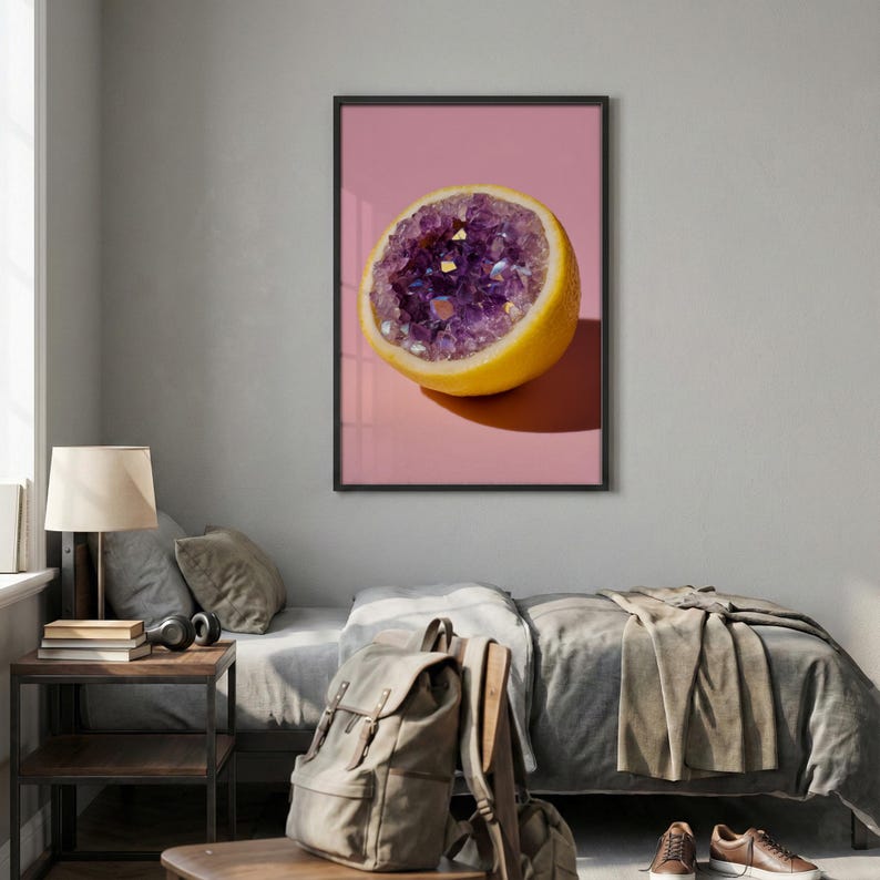 May include: A framed art print featuring a halved lemon with a purple crystal geode center. The artwork is set against a pink background, creating a striking contrast. The lemon's yellow rind and the geode's sparkling crystals are well-defined.