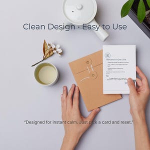 May include: A serene image with a white teapot, a teacup with tea, and a brown envelope. A card with the text "Reframe in One Line" is held by a person. The image includes the text "Clean Design • Easy to Use" and "Designed for instant calm. Just pick a card and reset."