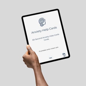 Puede incluir: Una tableta negra que muestra "Anxiety Help Cards" con el texto "60-Second Anxiety Help Cards Cards" y "10 printable cards + instant calm". La tableta est&aacute; sujeta por una mano sobre un fondo gris.