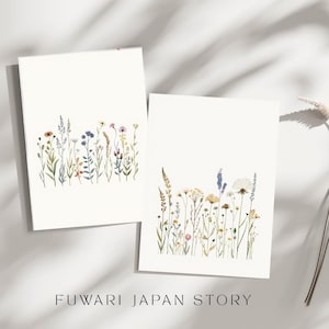以下が含まれることがあります： 2枚の白いカード。水彩画で野花が描かれています。カードの下部には、さまざまな色とりどりの花と緑が描かれています。「FUWARI JAPAN STORY」の文字が画像の下部に印刷されています。