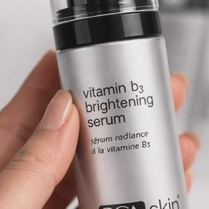May include: A silver bottle of PCA Skin Vitamin B3 Brightening Serum. The bottle has a black pump and a clear cap. The label includes the text "vitamin b3 brightening serum" and "1 fl oz/30mL".