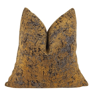 May include: A square throw cushion featuring a textured fabric with a deep mustard yellow base colour and an intricate, dark brown abstract pattern that resembles a distressed or weathered surface across the entire front of the cushion.