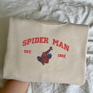 Puede incluir: Una taza de cer&aacute;mica blanca con un asa negra y el texto "But First, Coffee" en negro, con una fuente de estilo manuscrito. La taza est&aacute; sobre una superficie blanca.