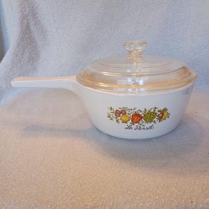 May include: White saucepan with a clear glass lid and a long handle. The pan features a colorful illustration of vegetables and the text "Le Persil". A vintage kitchenware item.