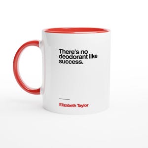 Könnte beinhalten: Weißer Keramikbecher mit rotem Innenraum und Henkel. Der Becher zeigt das Zitat "There's no deodorant like success" in schwarzem Text, zugeschrieben an Elizabeth Taylor.