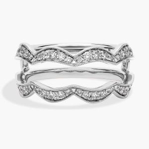 Puede incluir: Dos anillos de plata con un diseño ondulado, cada uno adornado con pequeños diamantes brillantes. Los anillos están apilados, mostrando sus intrincados detalles y elegante artesanía. Los diamantes están engastados a lo largo de los bordes curvos.