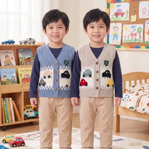 Könnte beinhalten: Zwei Kinder tragen langärmelige marineblaue Hemden, beigefarbene Hosen und weiße Turnschuhe. Ein Kind trägt eine blaue Strickweste mit weißem Karomuster und Auto-Applikationen, das andere eine beige Strickweste mit ähnlichen Autodetails.