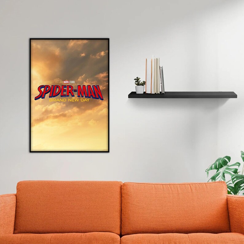 May include: A rectangular framed wall poster featuring a golden sunset sky background with the red and blue text Spider-Man Brand New Day and the Marvel Studios logo centered above the title in a black frame hanging on a plain white wall.