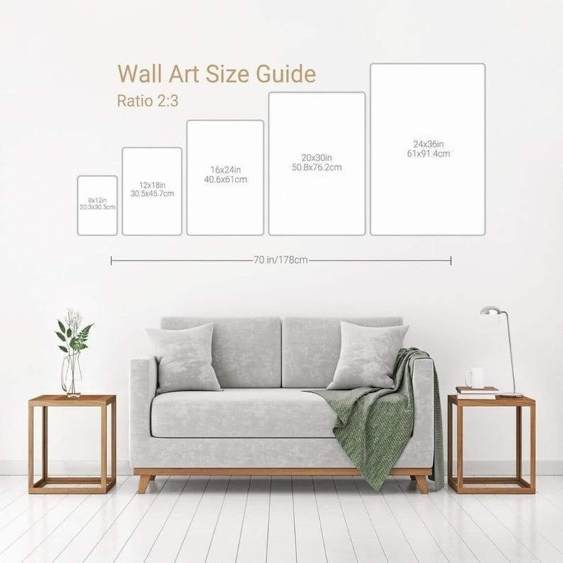 May include: A wall art size guide chart displaying a 2:3 ratio with five rectangular outlines labeled 6x12in, 12x18in, 16x24in, 20x30in, and 24x36in. Below, a light gray two-seater sofa with a green throw blanket sits between two wooden side tables.