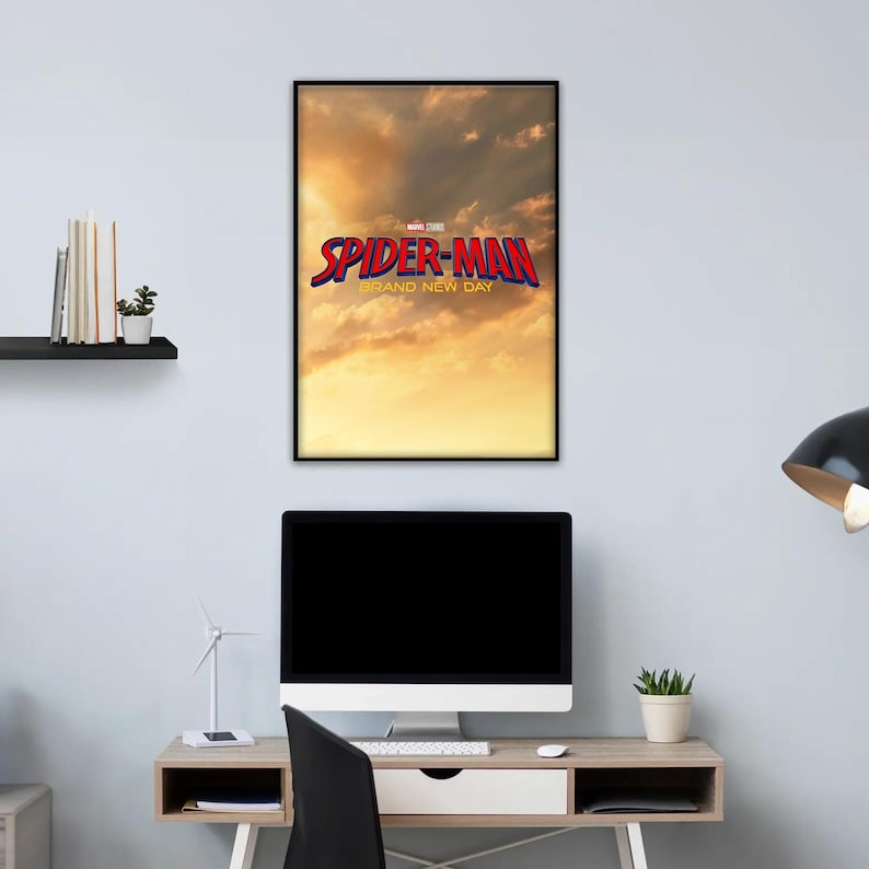 May include: A framed rectangular wall poster featuring a golden sunset sky background with the red and blue text Spider-Man Brand New Day and the Marvel Studios logo centered in the upper portion of the print, displayed in a black frame.