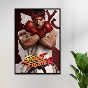 May include: A framed poster featuring a martial artist with a red headband and red boxing gloves, arms crossed over a white sleeveless gi. The text Street Fighter is printed in bold yellow and red letters at the bottom of the graphic design.