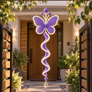 May include: A hanging crochet decoration featuring a purple butterfly with a white border at the top, connected to a long, spiraling purple and white crochet tail that ends with a clear, faceted crystal drop suspended from a small metal ring.