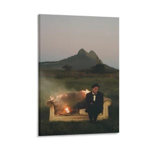 May include: A canvas print depicts a person in a black tuxedo sitting on a beige sofa engulfed in flames. The background features a mountain range and a field under a dusky sky. The artwork evokes a sense of drama and contemplation.