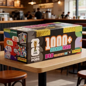 May include: A collector's box for the FIFA World Cup 2026, featuring the FIFA trophy and the text "1000+ Stickers Inside." The box is black with gold, pink, and purple accents, and includes 143 packets of stickers.