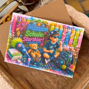 Könnte beinhalten: Eine rechteckige Grußkarte mit einer farbenfrohen Illustration eines Kindes im Weltraum-Outfit, das Seifenblasen macht. Die Karte zeigt den Text Mission Schule: Startklar!, einen Teddybären, einen Rucksack, Bücher und Stifte vor riesigen Buntstiften und Blumen.