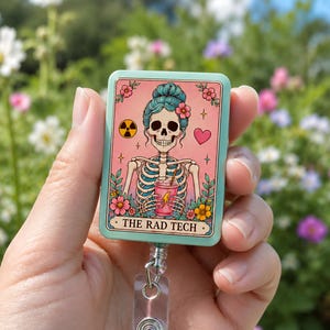 May include: A rectangular badge reel with a light green border featuring a graphic of a skeleton with blue hair holding a pink drink. The design includes flowers, a heart, a radiation symbol, and the text THE RAD TECH in a cream-colored banner.