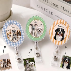 May include: Three oval badge reels featuring custom pet portraits. The left reel has a blue gingham border with three dogs named Charlie, Daisy, and Oliver. The center reel has a green polka dot border with two dogs named Aria and Finn. The right reel has an orange striped border with a dog named Baron.
