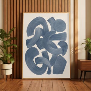 May include: A framed wall art print featuring a series of overlapping, thick, brushstroke-style abstract shapes in shades of muted blue on a plain white background. The artwork is enclosed in a simple, light-toned wooden frame.