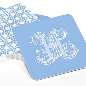 May include: A stack of light blue coasters with a white woven pattern on the bottom coaster and a white monogram of the letter "H" on the top coaster.