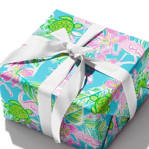 May include: A blue gift box with a white ribbon. The box is wrapped in paper with a tropical print featuring pink flamingos, green sea turtles, and palm leaves.