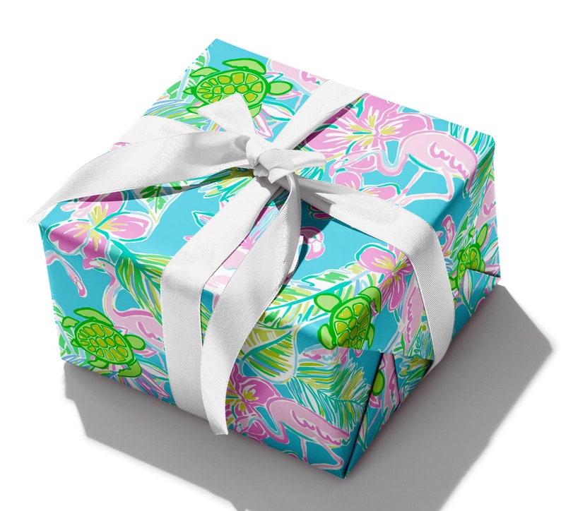 May include: A blue gift box with a white ribbon. The box is wrapped in paper with a tropical print featuring pink flamingos, green sea turtles, and palm leaves.