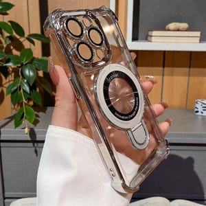 May include: Clear phone case with a silver frame and a circular ring holder. The case has a protective design around the camera lenses. The ring holder has the text "Innovation changes the world".
