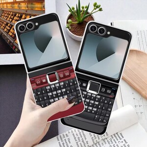May include: Two phone cases with a retro flip phone design. One case is red and black, the other is black. Both have a full keyboard and a clear screen area. The cases are shown side by side.