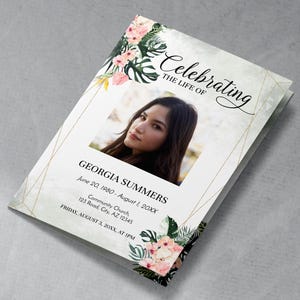 Op de afbeelding: Een herdenkingsprogramma met een foto van een vrouw, bloemaccenten en gouden geometrische lijnen. De tekst luidt "Celebrating the Life of Georgia Summers" met data en locatiegegevens. Het ontwerp bevat roze en groene bloemstukken.