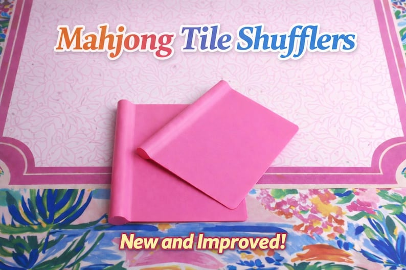 May include: Two bright pink rectangular Mahjong tile shufflers with a rolled edge on one side. The text Mahjong Tile Shufflers is displayed at the top, and the text New and Improved! is displayed at the bottom of the image.
