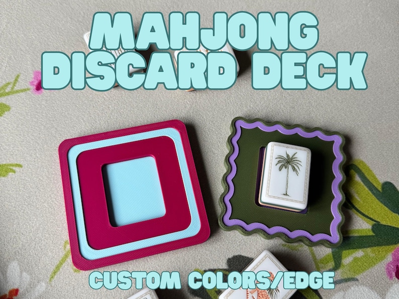 May include: A close-up of two Mahjong discard deck holders. One is a square with a magenta frame and a light blue interior. The other is a green frame with a purple scalloped edge, holding a white tile with a palm tree. Text reads "MAHJONG DISCARD DECK" and "CUSTOM COLORS/EDGE".