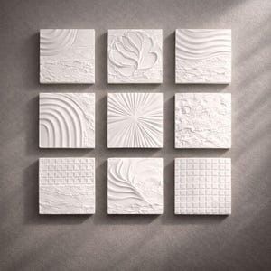 May include: Nine white square tiles with textured designs, including waves, floral patterns, and geometric shapes. The tiles are arranged in a three-by-three grid against a gray background, showcasing a variety of relief patterns.