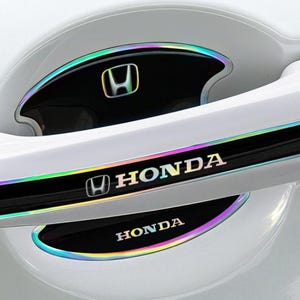 Puede incluir: Adornos blancos para manijas de puertas de automóviles con ribete iridiscente. El logotipo de Honda y el nombre de la marca se muestran en letras plateadas sobre un fondo negro. Los adornos están diseñados para adaptarse alrededor de la manija de la puerta y el ojo de la cerradura.