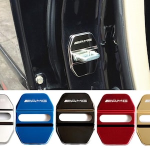 Puede incluir: Cubiertas de cerraduras de puertas de coche en plata, azul, negro, rojo y dorado. Cada cubierta tiene el logotipo AMG en blanco. Las cubiertas se muestran instaladas en una puerta de coche y también se muestran en una fila debajo.