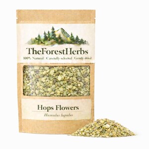 Puede incluir: Una bolsa de papel marrón con flores de lúpulo secas con una ventana transparente y un pequeño montón de flores de lúpulo. La bolsa tiene el texto "TheForestHerbs" y "Hops Flowers" impreso. El fondo es blanco.