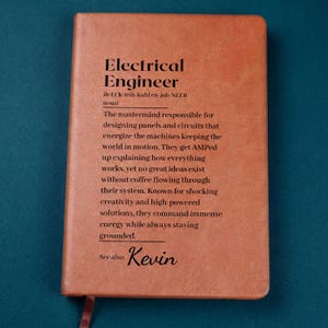 May include: A brown leather-bound notebook with the words "Electrical Engineer" printed in black. The text describes the role of an electrical engineer. The name "Kevin" is also printed on the notebook.