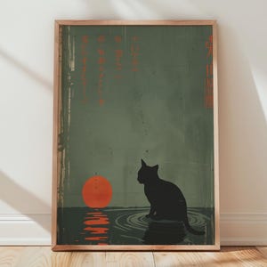 May include: Framed art print featuring a black cat silhouette sitting in water, with a vibrant orange sun setting in the background. The artwork has a Japanese aesthetic, with text in the upper portion and a wooden frame.