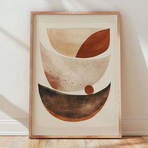 May include: A framed abstract art print featuring layered, curved shapes in shades of brown, beige, and rust. The artwork has a minimalist design with a warm, earthy color palette. The wooden frame complements the artwork's neutral tones.