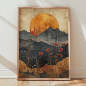 May include: A framed art print depicting a sunset over a mountain range. The image shows a large orange sun, silhouetted mountains, and red flowers. The print is in a wooden frame and is leaning against a white wall.
