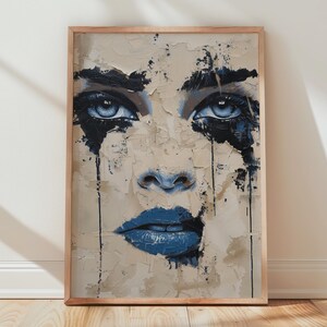 Peut inclure: Impression d'art de portrait abstrait représentant un visage de femme avec des yeux et des lèvres bleus. L'œuvre d'art a un aspect vieilli et texturé avec des accents bleu foncé et un fond neutre. L'impression encadrée est affichée contre un mur blanc et un sol en bois.