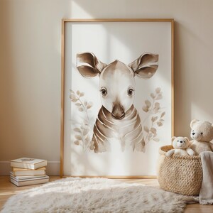 May include: Watercolor print of a baby animal with large ears and striped markings, framed in a light wood. The artwork is in shades of brown and beige, with leafy accents. A woven basket with stuffed animals sits nearby.