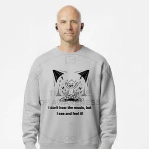 May include: A light gray sweatshirt with a black graphic and the text "I don't hear the music, but I see and feel it." The person is wearing khaki pants and black and white sneakers.