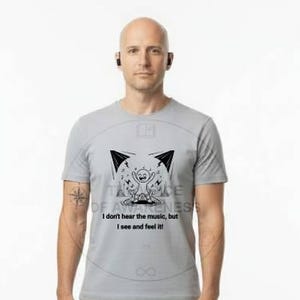 May include: A person wearing a gray t-shirt with a graphic design and the text "I don't hear the music, but I see and feel it." The person is also wearing khaki pants and white sneakers.
