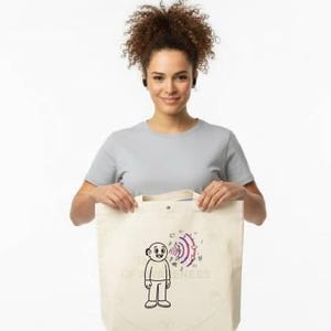 May include: A beige tote bag with a cartoon figure and sound wave design. The bag is held by a person wearing a gray t-shirt and khaki pants. The design features a person with sound waves emanating from their head.