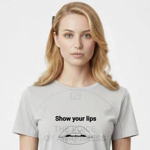 May include: A light gray t-shirt with the text "Show your lips" above a line drawing of lips. The shirt is short-sleeved and is being worn by a person.