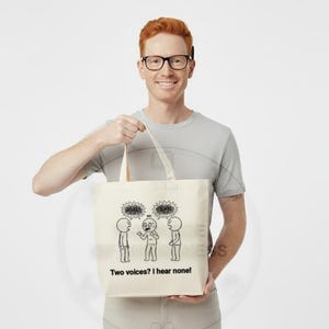 May include: A beige tote bag with a black and white cartoon illustration of three figures with thought bubbles. The text "Two voices? I hear none!" is below the illustration. The bag has a simple design and is held by a person.