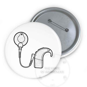 May include: White button featuring a black and white illustration of a cochlear implant and a hearing aid. The text "THE VOICE OF AWARENESS" is printed on the button. The button has a metal pin back.