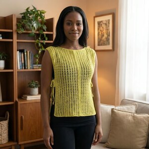 May include: A sleeveless, yellow crochet top with a round neckline and side ties. The top has a textured, open weave design. The person is wearing black leggings.