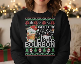 Op de afbeelding: Zwarte sweatshirt met een feestelijk vakantieontwerp. De afbeelding toont een cocktail met een kerstmuts, lichtslingers en de tekst "I'm full of Holiday Spirit, it's called Bourbon."